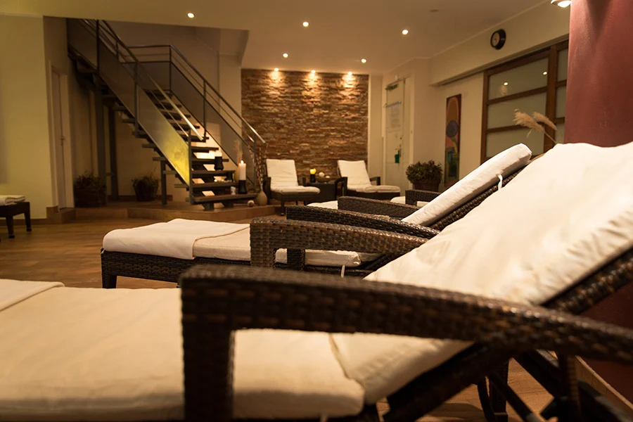 Relaxation room with loungers against a natural stone wall at Lokahi Loft Berlin